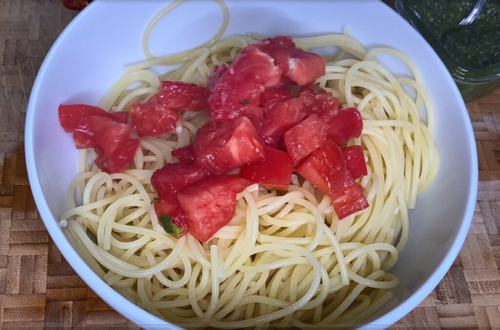 Schüssel mit gekochten Spaghetti und gehackten Tomaten