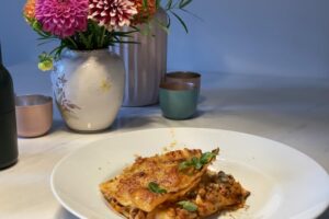 Teller Lasagne Bolognese auf Tisch mit Blumenvase