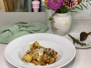 Teller mit Tortelloni und Pilzen auf gedecktem Tisch