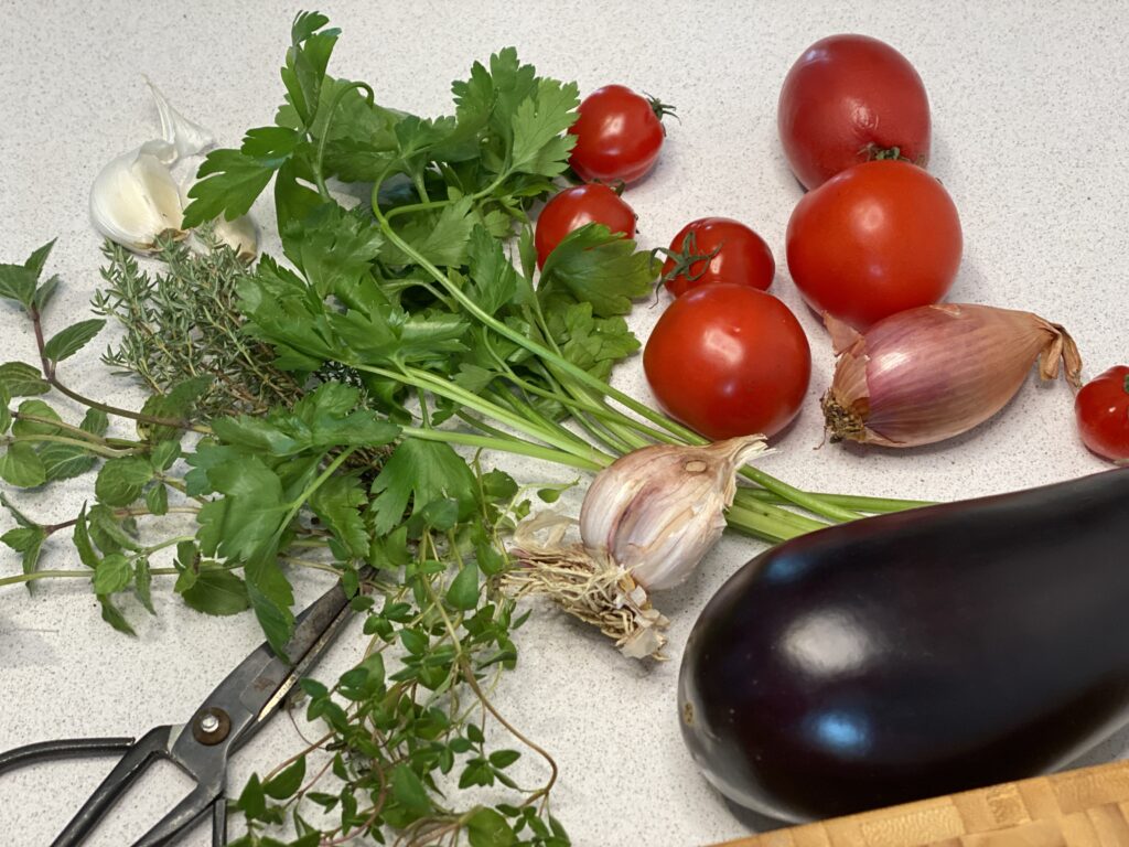 Aubergine, Kräuter, Tomaten, Schalotte und Knoblauch auf Arbeitsplatte