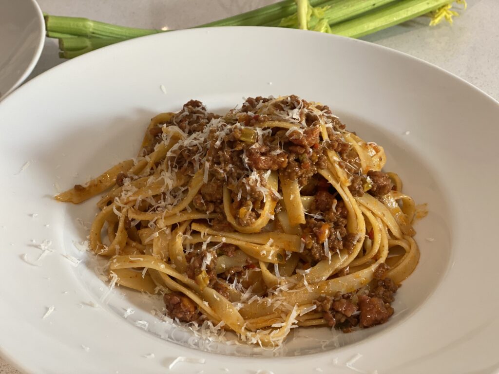 Tagliatelle mit Bolognese mischen und auf zwei Tellern verteilen